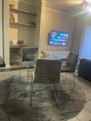 a dining room with chairs and a table and a tv at Tranquil 2 bed 2 bath studio in Sandton