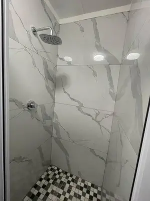 a shower with a glass door and a checkered floor at Tranquil 2 bed 2 bath studio in Sandton