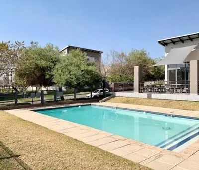 a swimming pool in front of a house at Tranquil 2 bed 2 bath studio in Sandton