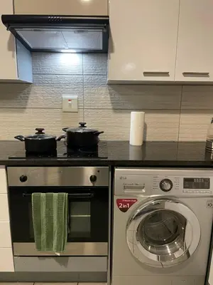 a kitchen with a stove and a washing machine at Tranquil 2 bed 2 bath studio in Sandton