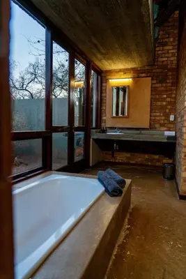 a bath tub in a room with a large window at The Riverine Lodge in Welgevonden Game Reserve
