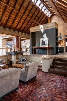 a living room with couches and a staircase in a building at The Riverine Lodge in Welgevonden Game Reserve