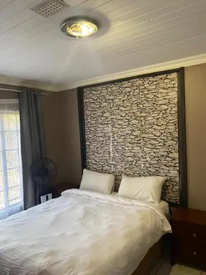 a bedroom with a large bed with a stone wall at Home Sweet Home Farmhouse in Nelspruit