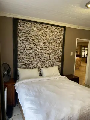 a large bed in a room with a stone wall at Home Sweet Home Farmhouse in Nelspruit