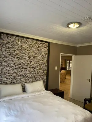 a bedroom with a stone wall with a bed at Home Sweet Home Farmhouse in Nelspruit