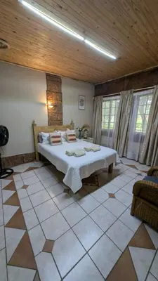a bedroom with a large bed and a wooden ceiling at La Mathil in Swartspruit