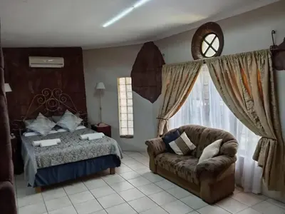 a bedroom with a bed and a couch and a window at La Mathil in Swartspruit