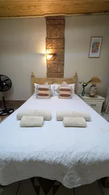 a large white bed with three pillows on it at La Mathil in Swartspruit