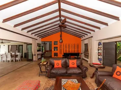 a living room with leather couches and a piano at African Dream Villa in White River