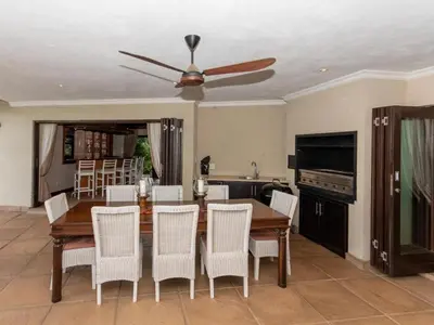 a dining room with a table and chairs and a ceiling fan at African Dream Villa in White River