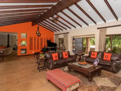 a living room with leather couches and a piano at African Dream Villa in White River