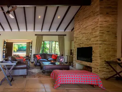 a living room with leather furniture and a stone wall at African Dream Villa in White River
