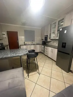 a kitchen with a refrigerator and a table and chairs at Tan 46 Park Acres in Nelspruit