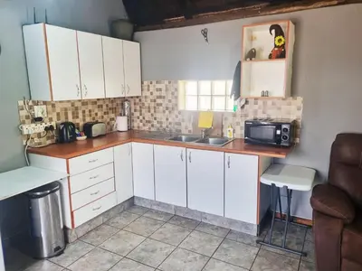 a kitchen with white cabinets and a sink and a microwave at Lyttelton Self-Catering Accommodation in Centurion