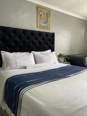 a large bed with a black headboard and white pillows at DA LIFE Guest House in Springs