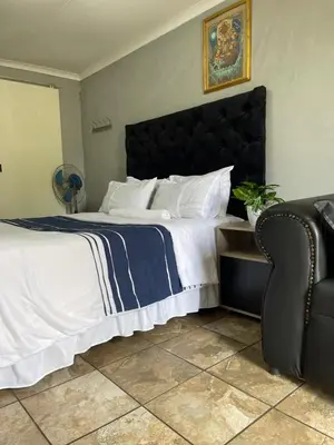 a bedroom with a large bed and a chair at DA LIFE Guest House in Springs