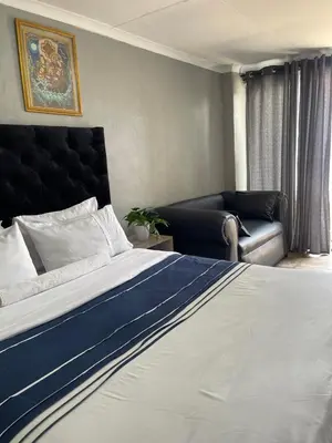 a bedroom with a large bed and a couch at DA LIFE Guest House in Springs