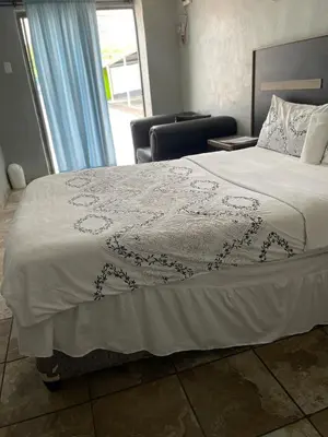 a bedroom with a bed and a chair and a window at DA LIFE Guest House in Springs