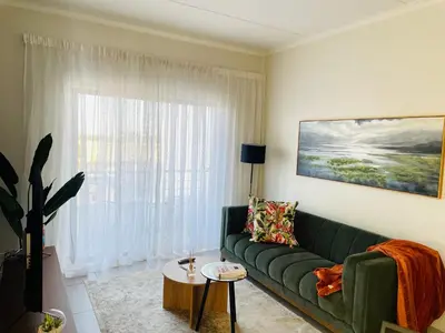 a living room with a green couch and a window at Peaceful Nest in Midrand