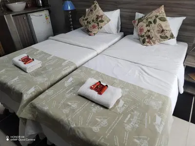 two beds in a room with white sheets and pillows at Home of peace and tranquility in Pretoria