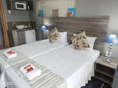 a bedroom with a large bed with white sheets and pillows at Home of peace and tranquility in Pretoria