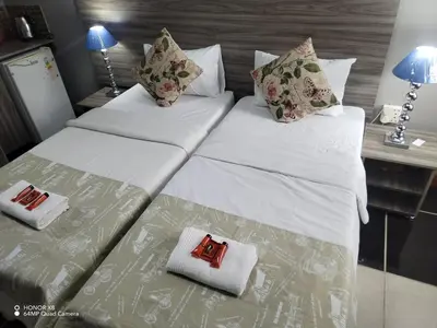 a bedroom with two beds with white sheets and pillows at Home of peace and tranquility in Pretoria