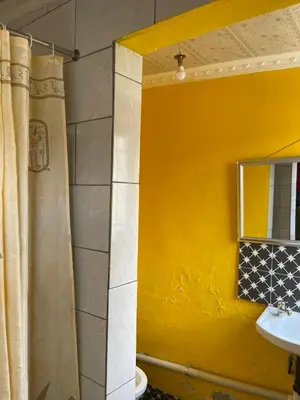 a bathroom with a yellow wall and a mirror at Good Time Guest House in Springs