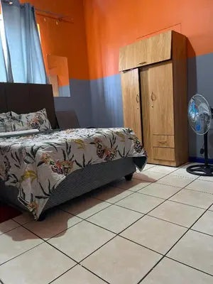 a bedroom with a bed and a small cabinet at Good Time Guest House in Springs