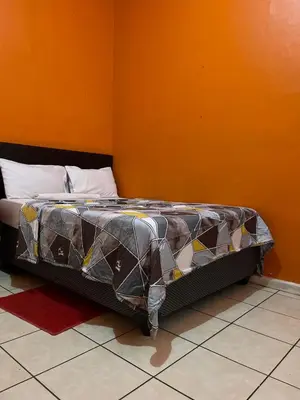 a bed in a room with an orange wall at Good Time Guest House in Springs