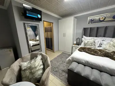 a bedroom with a bed and a mirror and a chair at StayComfyGuesthouseByPunky in Soshanguve