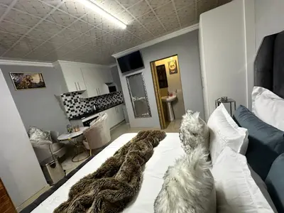 a dog sitting on a bed in a living room at StayComfyGuesthouseByPunky in Soshanguve