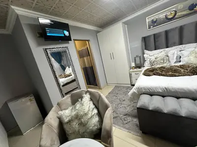 a bedroom with a bed and a mirror and a chair at StayComfyGuesthouseByPunky in Soshanguve