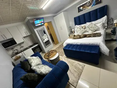 a bedroom with a large bed and a blue couch at StayComfyGuesthouseByPunky in Soshanguve