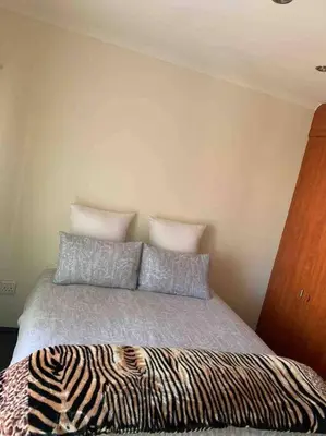 a bed with two pillows and a zebra blanket at 177 San Ridge Village in Midrand