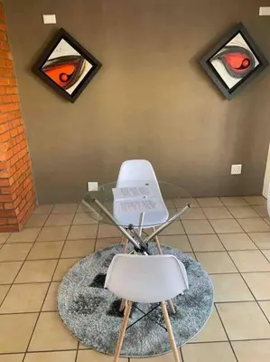 a glass table and a white chair in a room at 177 San Ridge Village in Midrand