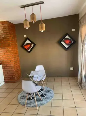 a room with two chairs and paintings on the wall at 177 San Ridge Village in Midrand