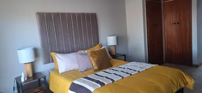 a bedroom with a bed with yellow sheets and pillows at Sandgrouse Guesthouse in Centurion
