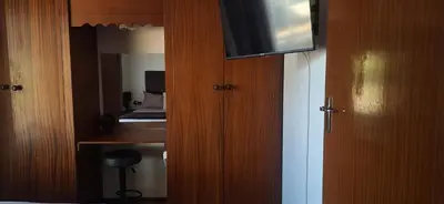 a room with a closet with a television and a bed at Sandgrouse Guesthouse in Centurion