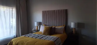 a bedroom with a large bed with yellow sheets and pillows at Sandgrouse Guesthouse in Centurion