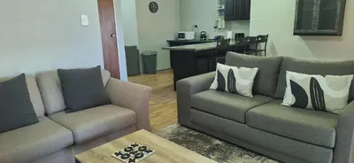 a living room with two couches and a kitchen at Sandgrouse Guesthouse in Centurion