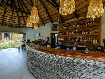a bar in a restaurant with chandeliers at Waterberg Game Park in Mokopane