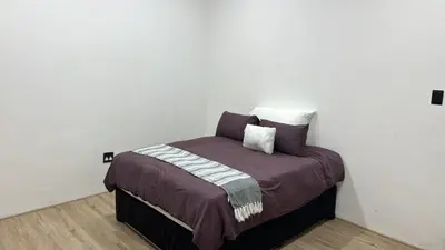 a bed in a room with a white wall at Golden Treasure - OFF GRID in Witbank