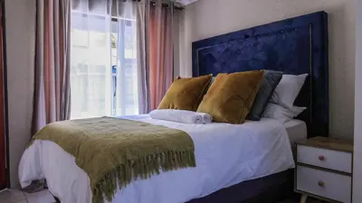 a bedroom with a bed with a blue headboard and a window at Nsuku Guest House in Phalaborwa