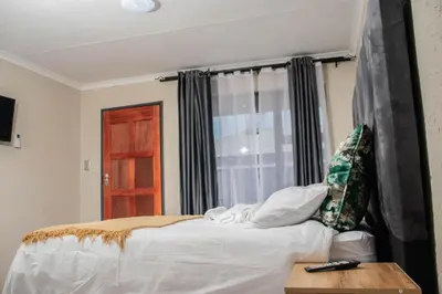 a bedroom with a bed with a window and a table at Nsuku Guest House in Phalaborwa