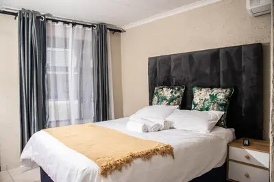 a bedroom with a large bed with a black headboard at Nsuku Guest House in Phalaborwa