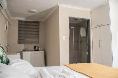 a bathroom with a shower and a bed in a room at Nsuku Guest House in Phalaborwa