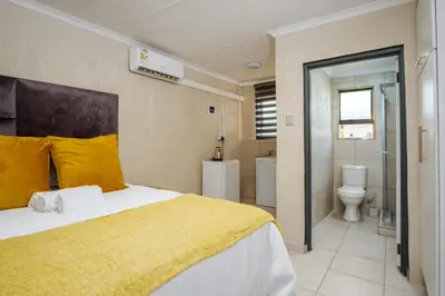 a bedroom with a bed and a bathroom with a toilet at Nsuku Guest House in Phalaborwa