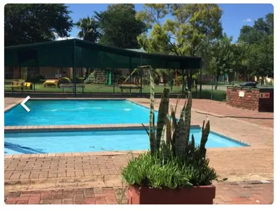 a swimming pool with a green canopy and a playground at 27 Pendleberry Grove, Chris Hani Drive, Bela-Bela in Bela-Bela