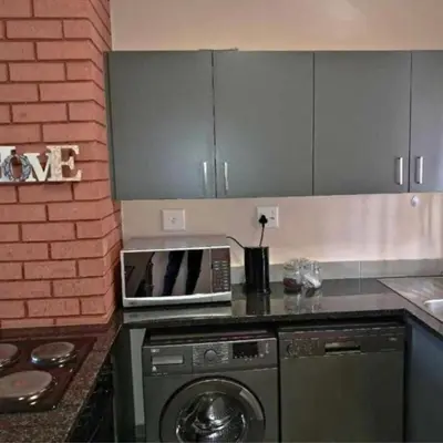 a kitchen with a microwave and a dishwasher at Waterfall Ridge Professional Apartment in Midrand