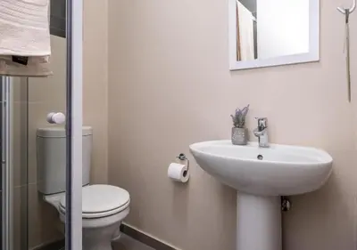 a white bathroom with a toilet and a sink at Waterfall Ridge Professional Apartment in Midrand